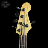 Close-up of a natural wood bass guitar headstock with six tuning pegs and the brand name 'Majest guitars' printed vertically, set against a solid black background.