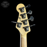 Close-up of the headstock of a bass guitar with four black tuning pegs and a light natural wood finish, shown against a solid black background. A Tone Shop watermark is visible in the top left corner.