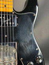 Close-up of a black electric guitar with visible brand name on a gray background