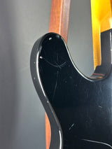 Close-up of a guitar neck with a black pickguard and wooden fretboard.