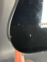 Close-up of a guitar's black pickguard with visible scratches and a wooden neck.