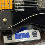 Black electric guitar on a digital scale displaying weight