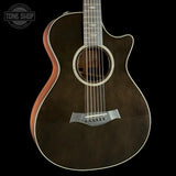 Acoustic guitar with a dark brown finish on a black background, featuring the Tone Shop logo.