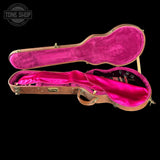 Guitar case with pink interior on a black background, featuring 'Tone Shop' logo.