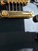 Close-up of a gold guitar tuning peg on a black guitar body