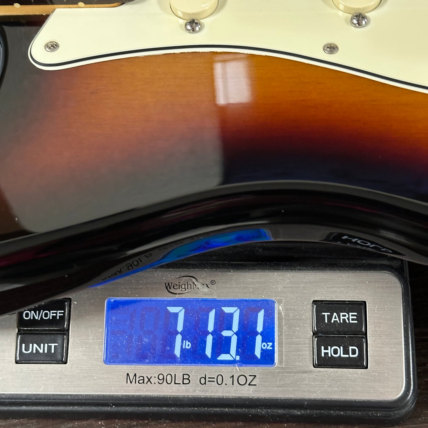 Digital scale displaying weight of a guitar, with a close-up on the scale's display.