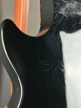 Close-up of a guitar neck with a black finish and visible wood grain.