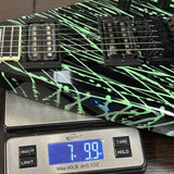 Electric guitar with a black and green design on a digital scale displaying weight.