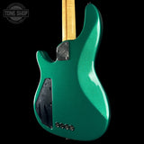 Green electric guitar with a black pickguard on a black background, featuring 'Tone Shop' logo.