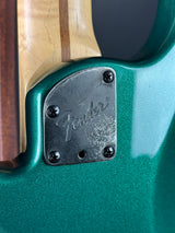Close-up of a Fender guitar with a green finish and wooden neck.