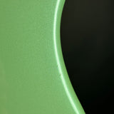 Close-up of a curved light green metallic surface with a dark black background visible on the right side.