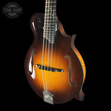 Wooden mandolin with a dark brown finish on a black background, featuring the Tone Shop logo.