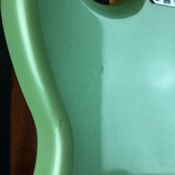 Close-up of a mint green electric guitar body showing the wood grain finish and a small circular defect on the surface.