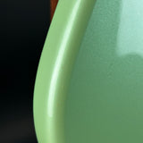 Close-up of a glossy light green curved surface, likely part of a product body, with a dark black background visible on the left.