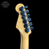 Guitar headstock with blue tuning pegs on a black background, featuring 'Tone Shop' logo.