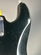 Close-up of a black guitar neck with visible wear on a gray background