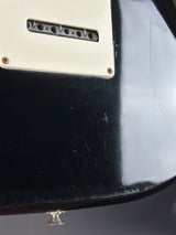 Close-up of a guitar with a visible brand logo on a dark background