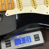 Digital scale displaying weight of a guitar on a wooden surface