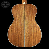 Back view of a wooden acoustic guitar with 'Tone Shop' logo.