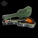 Acoustic guitar in a hard-shell case with 'Tone Shop' logo.