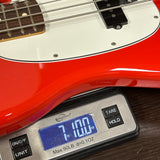 Red electric bass guitar on a digital scale displaying weight.