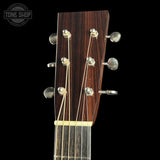 Close-up of a guitar headstock with tuning pegs on a black background, featuring the Tone Shop logo.