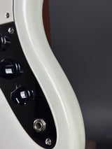 Close-up of a guitar's control panel with knobs and an input jack on a dark background