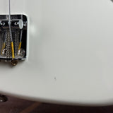 Close-up of a guitar's bridge and tuning pegs on a white guitar body.