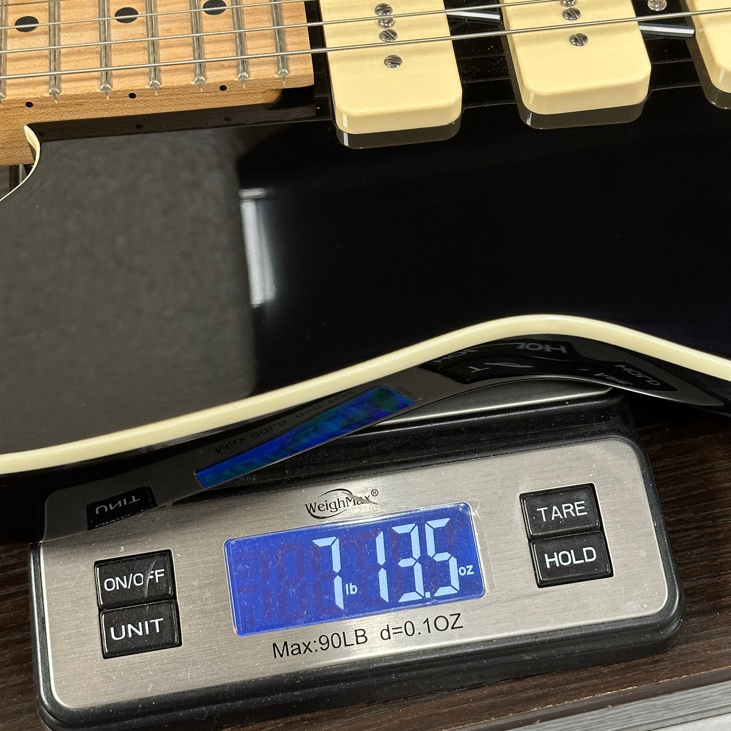 Digital scale displaying weight of a guitar on a wooden surface