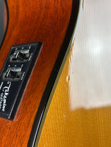 Close-up of a Takamine guitar with control panel and wood finish.