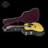 Acoustic guitar in an open case with 'Tone Shop' logo in the corner.