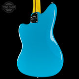 The back of a Fender electric guitar in a vibrant turquoise blue finish, featuring a yellow neck and a black Fender logo plate, set against a solid black background.