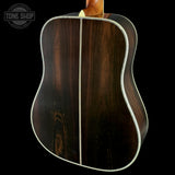 Back view of a wooden acoustic guitar with 'Tone Shop' logo.