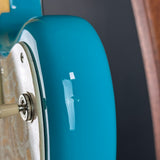 Close-up of a turquoise blue guitar body with a glossy finish, showing a small chip on the surface and part of the silver hardware.