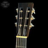 Close-up of a guitar headstock with tuning pegs on a black background, featuring 'Tone Shop' branding.