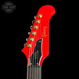 Red guitar headstock with 'Gibson' branding on a black background