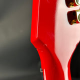 Close-up of a red guitar with a gold pickguard on a dark background