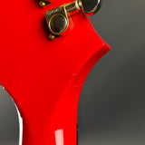 Close-up of a red electric guitar with a gold tuning peg on a gray background