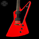 Red electric guitar with a black pickguard on a black background, featuring 'Tone Shop' branding.