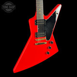 Red electric guitar with a black pickguard on a black background, featuring 'Tone Shop' branding.