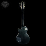 Black electric guitar with a visible brand logo on a black background