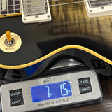 Guitar being weighed on a digital scale with a blue display.