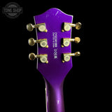 Close-up rear view of a purple electric guitar headstock with six gold tuning pegs and white printed model text on a black background.
