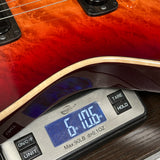 Guitar being weighed on a digital scale with a red finish