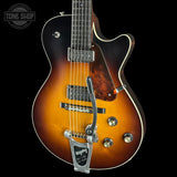 A close-up of a Gibson electric guitar body in a sunburst finish, showing the bridge, pickups, and control knobs against a black background.