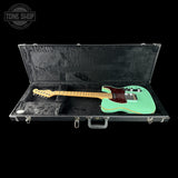 Turquoise electric guitar in a black case with 'Tone Shop' logo.