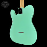 Turquoise electric guitar body on a black background with 'Tone Shop' logo.