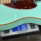 Teal electric guitar on a digital scale displaying weight.