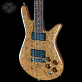 Electric bass guitar with a unique wood finish on a black background, featuring the Tone Shop logo.