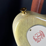 Close-up of a wooden product with a gold cap and red logo on a dark background